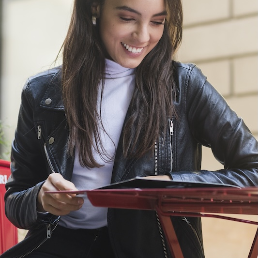 fashionable-smiling-young-woman-reading-menu-card-outdoor-cafe